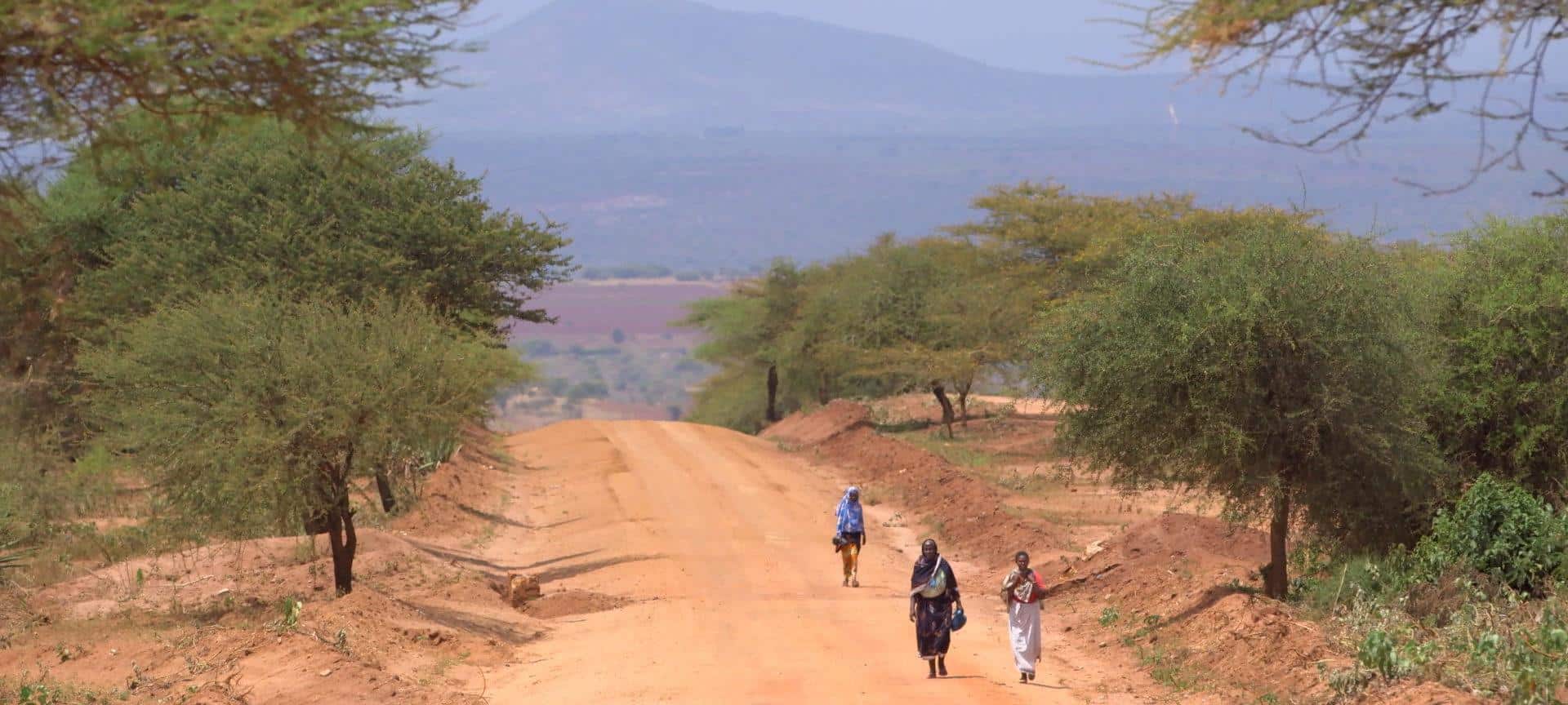 Three women walk along a dirt road in Ethiopia